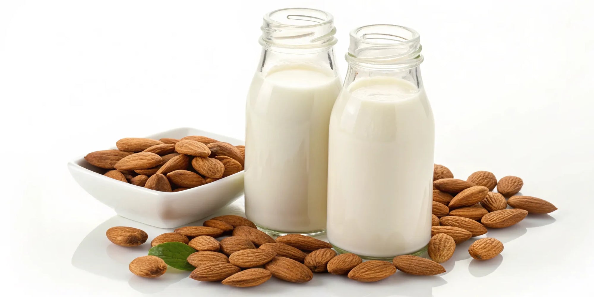 Almond formula vs dairy formula comparison with almonds and two bottles of milk.