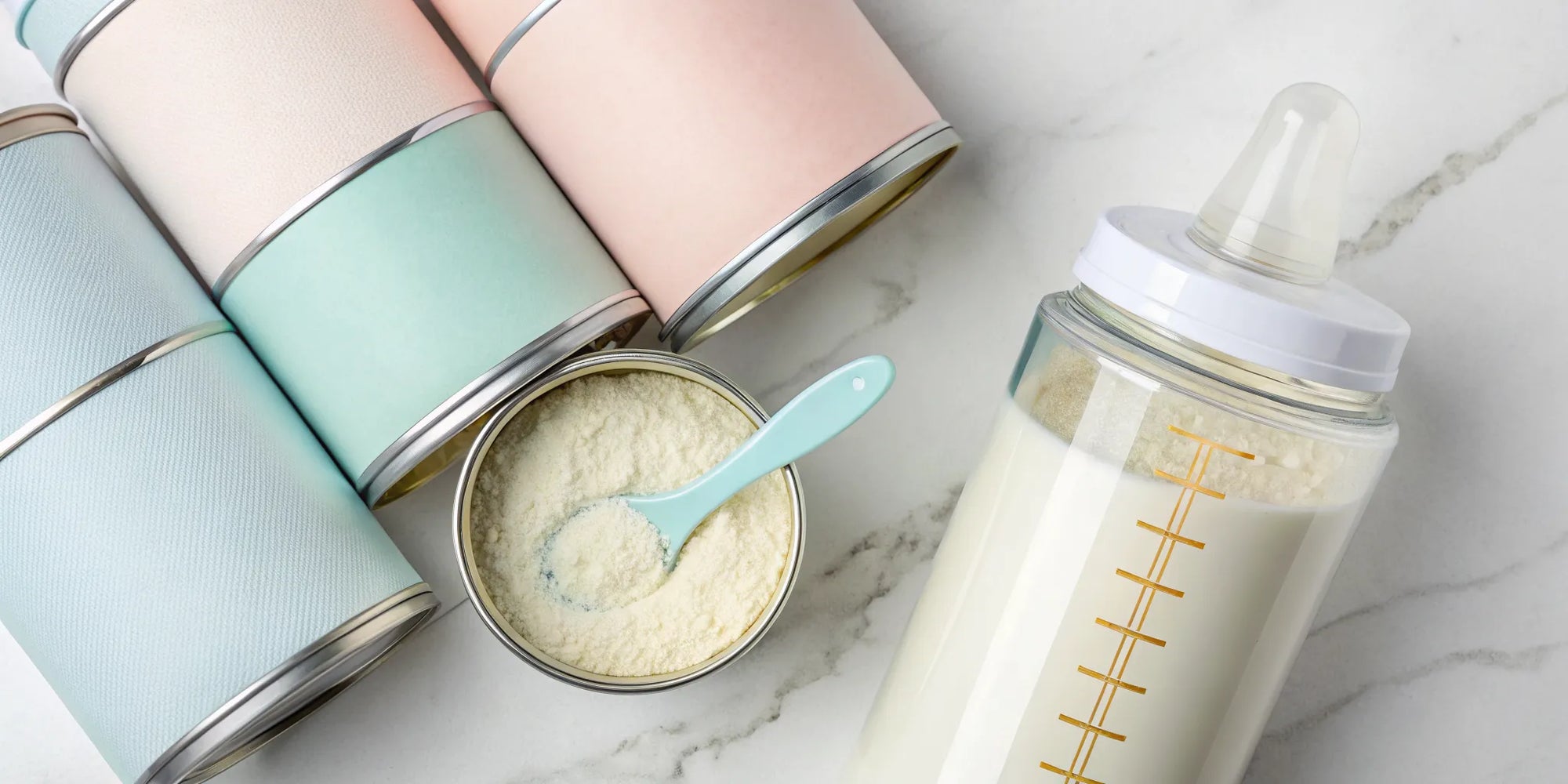 A can of sensitive baby formula with a scoop and a prepared bottle ready for a baby.