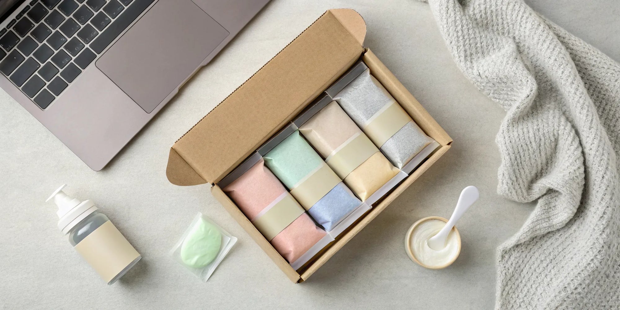 A box of free baby formula samples and baby care items next to a laptop.
