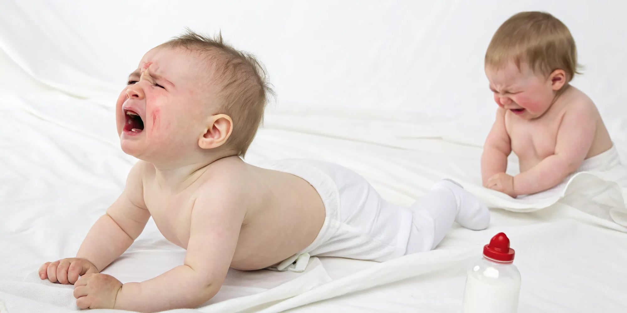 Two crying babies, one with red cheeks, showing signs of discomfort from CMPA vs normal gas.