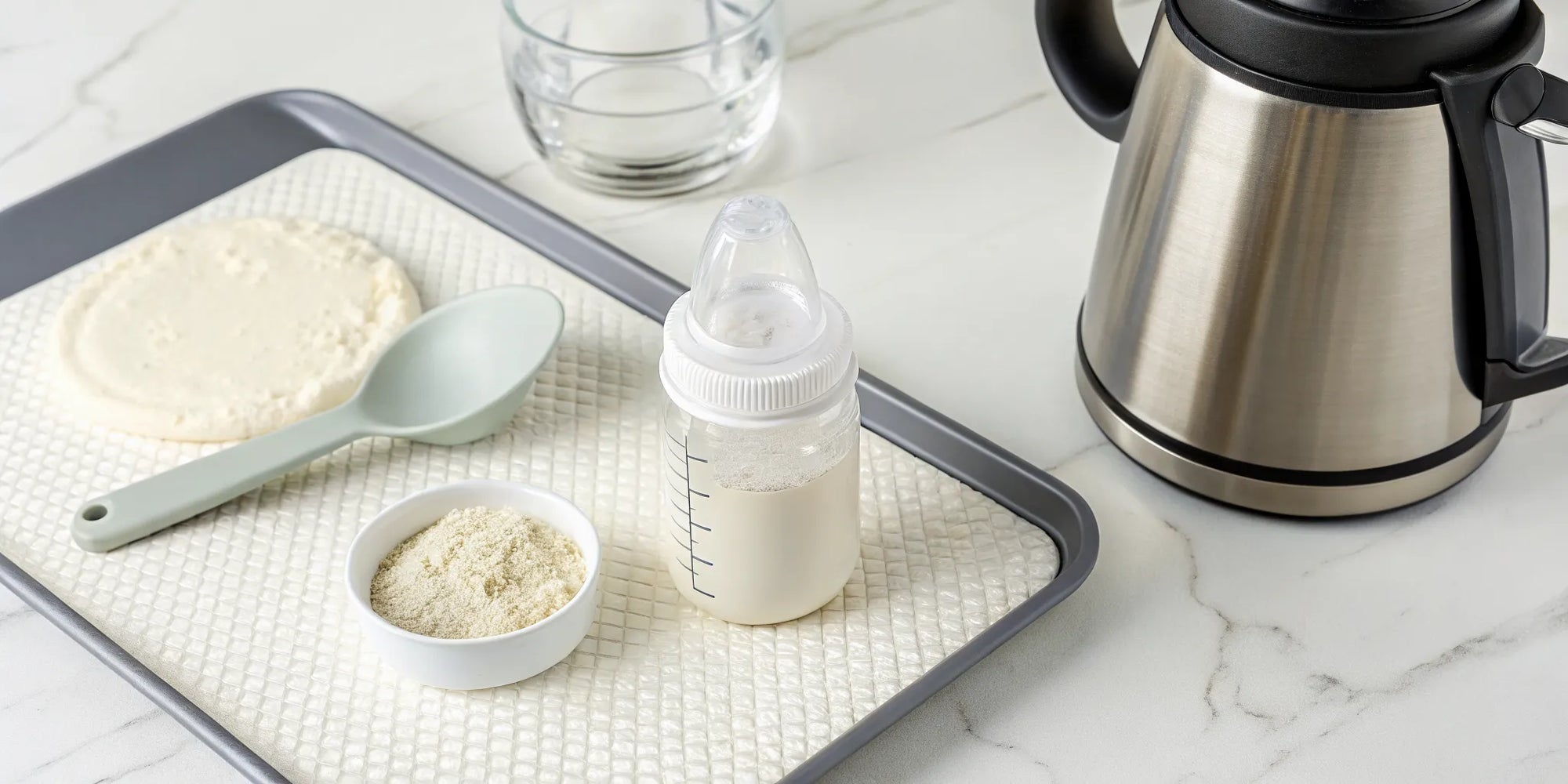 Baby bottle, formula powder, and kettle on a tray for safe preparation.